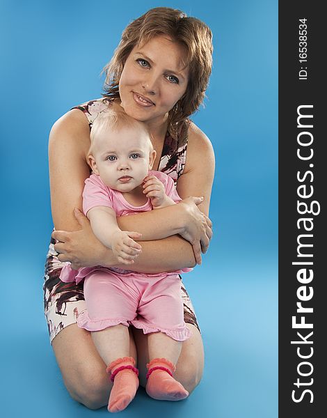 Young and beautiful mother with her sweet little daughter isolated on blue. Young and beautiful mother with her sweet little daughter isolated on blue.