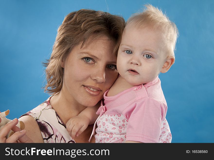 Young and beautiful mother with her sweet little daughter isolated on blue. Young and beautiful mother with her sweet little daughter isolated on blue.