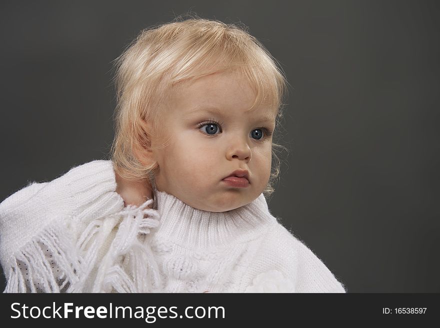 Beautiful little girl the blonde on a grey background. Beautiful little girl the blonde on a grey background