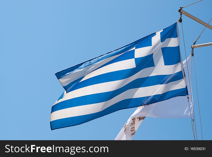 The greek flag waving from the top of a boat