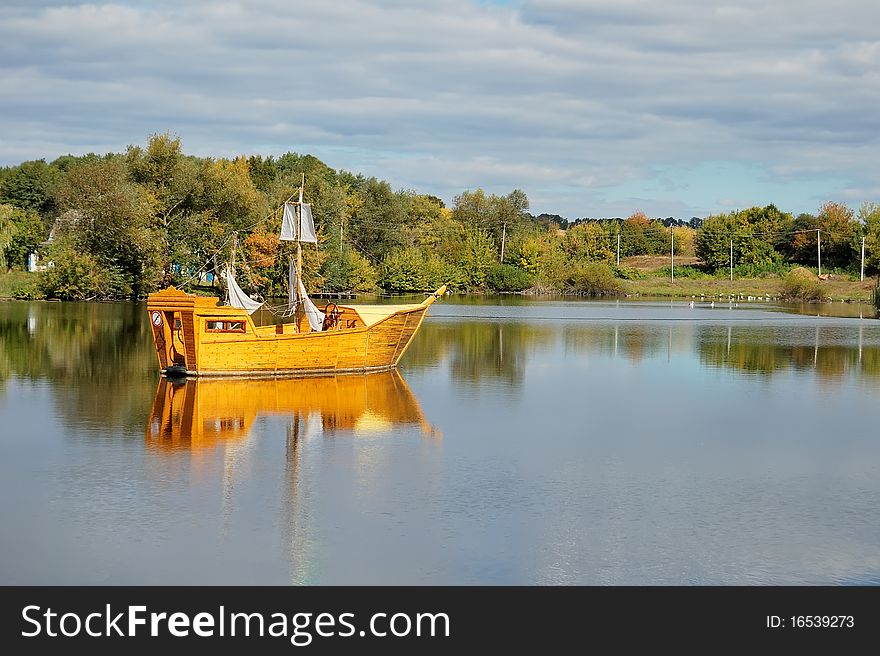 Age-old wooden sailing-vessel on a lake, autumn