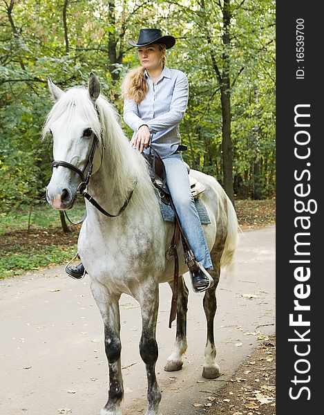 Young horsewoman sits on a white horse