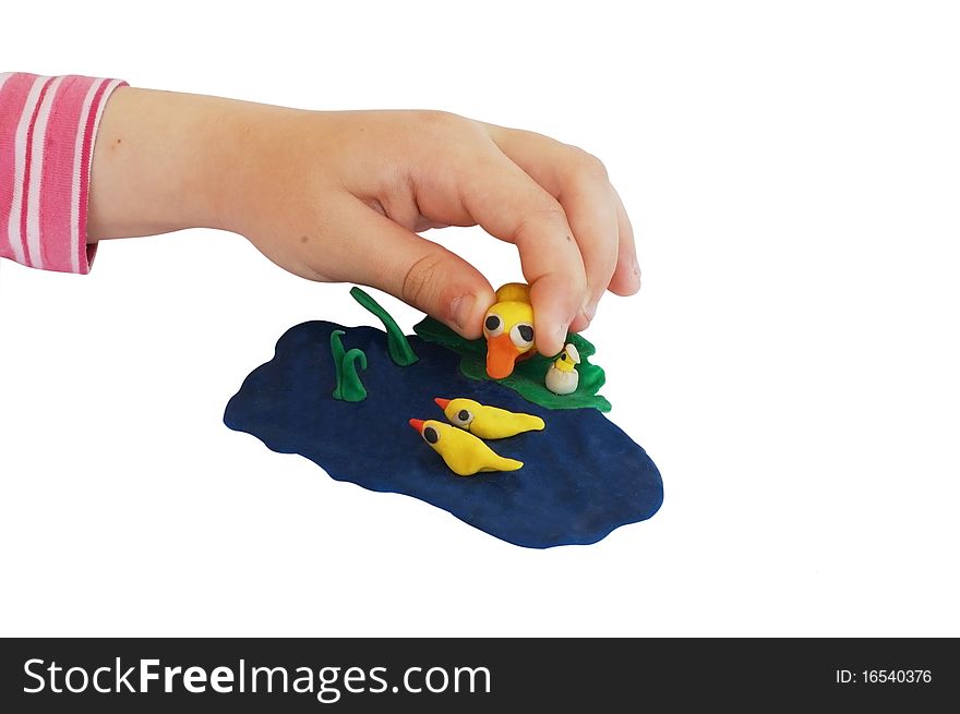 Child hand makes a plasticine composition of lake with ducks. isolated on white
