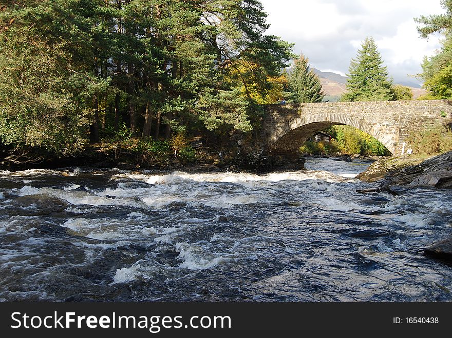 An old stone bridge spans the river dochart over the falls near Killin. An old stone bridge spans the river dochart over the falls near Killin