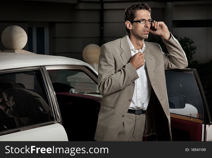 Young man speaking the phone next to the car