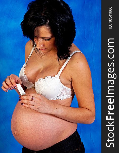 Pregnant woman with a pregnancy test on the blue mosaic background. Pregnant woman with a pregnancy test on the blue mosaic background
