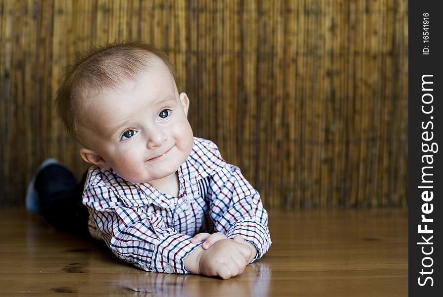 The small cheerful kid lie on a floor. The small cheerful kid lie on a floor.