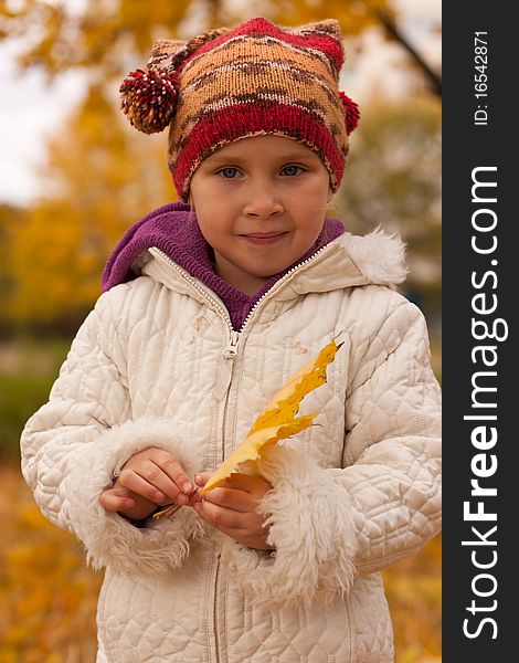 Girl in cute hat with a heap of maple leaves close up against autumn nature. Girl in cute hat with a heap of maple leaves close up against autumn nature