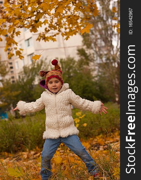 Beautiful girl in funny hat jumping with maple leaves against autumn nature. Beautiful girl in funny hat jumping with maple leaves against autumn nature