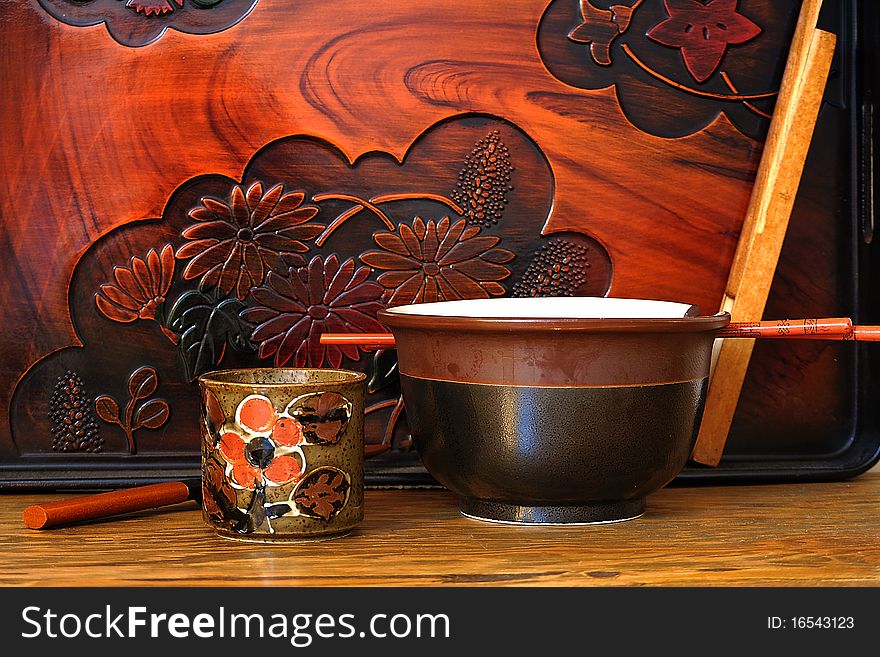 Japanese tea cup, soup bowl, chop sticks shown against a ornate tray. Japanese tea cup, soup bowl, chop sticks shown against a ornate tray