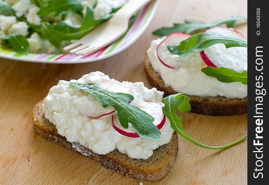 Two bread with cottage cheese, radish and arugula for breakfast