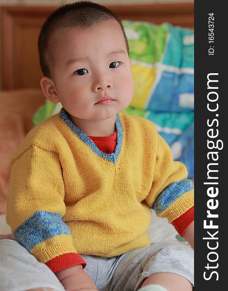 Lovely chinese baby sitting on the bed. Lovely chinese baby sitting on the bed