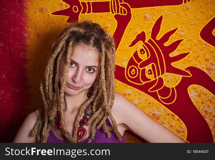 Portrait of white attractive female teenager with dreadlocks on the ethnic bright  painted canvas background. Portrait of white attractive female teenager with dreadlocks on the ethnic bright  painted canvas background