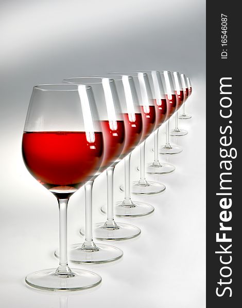 Raw of glasses with red wine on neutral background