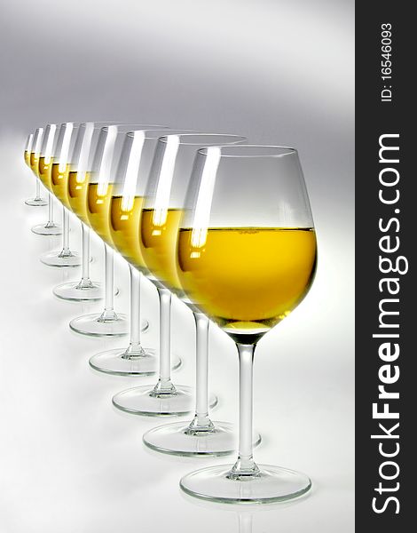 Raw of glasses with white wine on neutral background