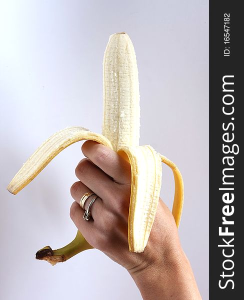 Peeled banana held in the hand by a woman