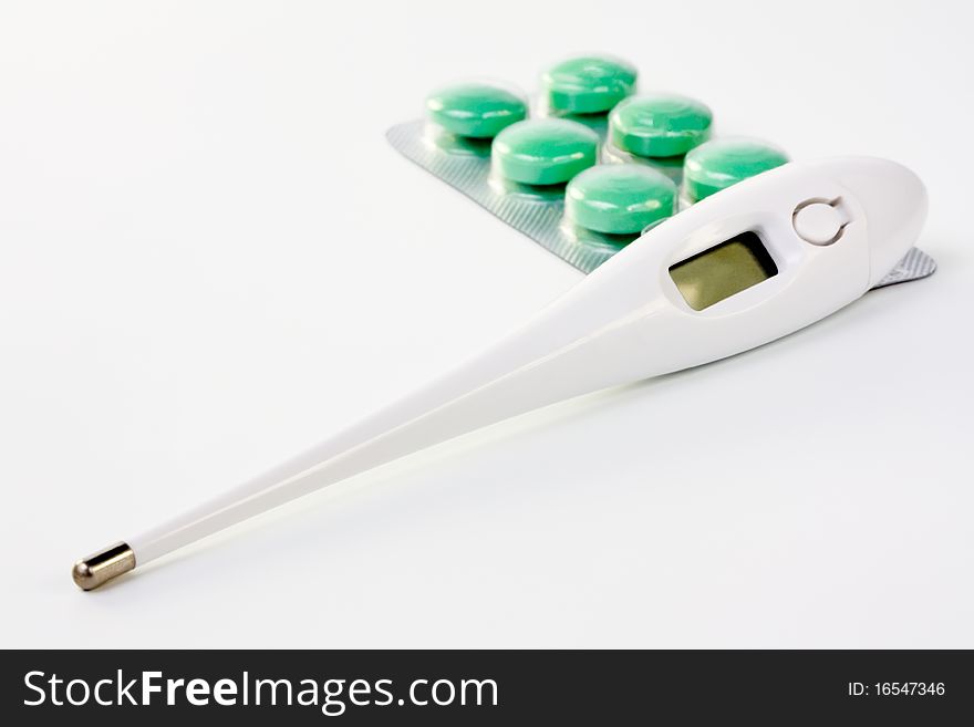 Electronic medical thermometer and pills closeup