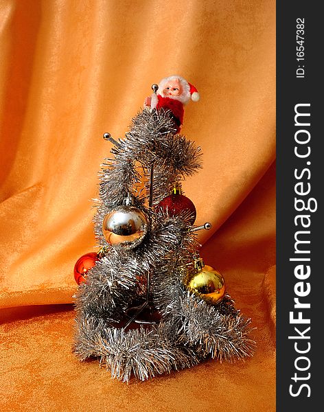 A cup stand on an orange background decorated with a toy Santa, white garland and Christmas-tree balls. A cup stand on an orange background decorated with a toy Santa, white garland and Christmas-tree balls.