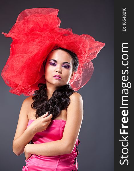 Dreaming beautiful brunette woman in red tulle hat embracing herself