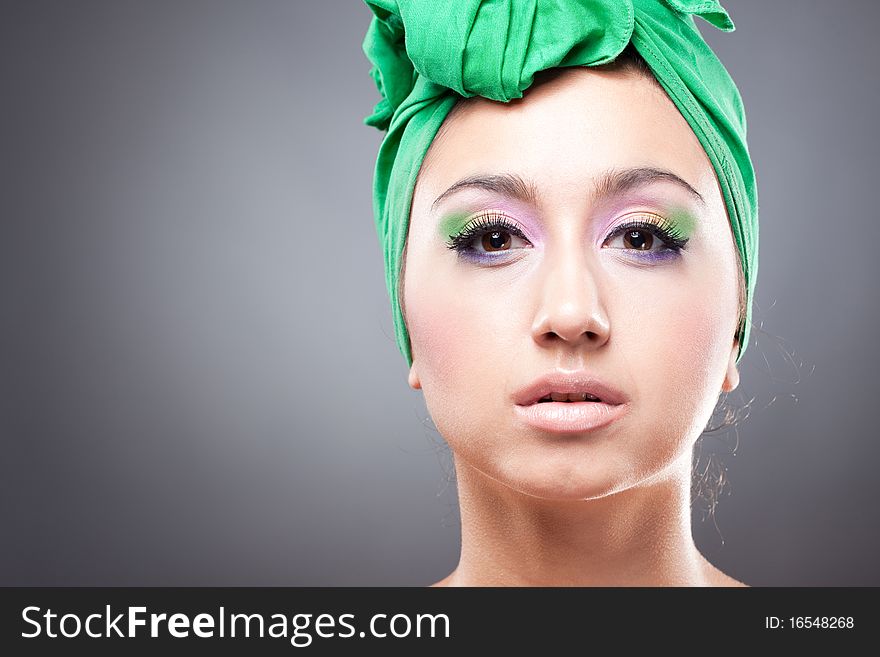 Beautiful woman with pink-green makeup in green hat looking at camera. Beautiful woman with pink-green makeup in green hat looking at camera