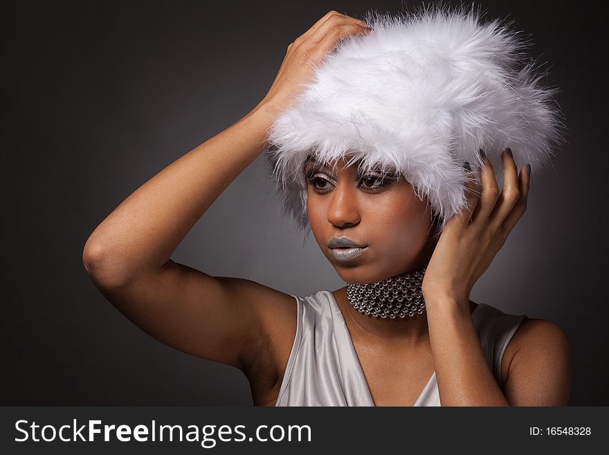 African woman in white hat and silver necklace holding head with hands