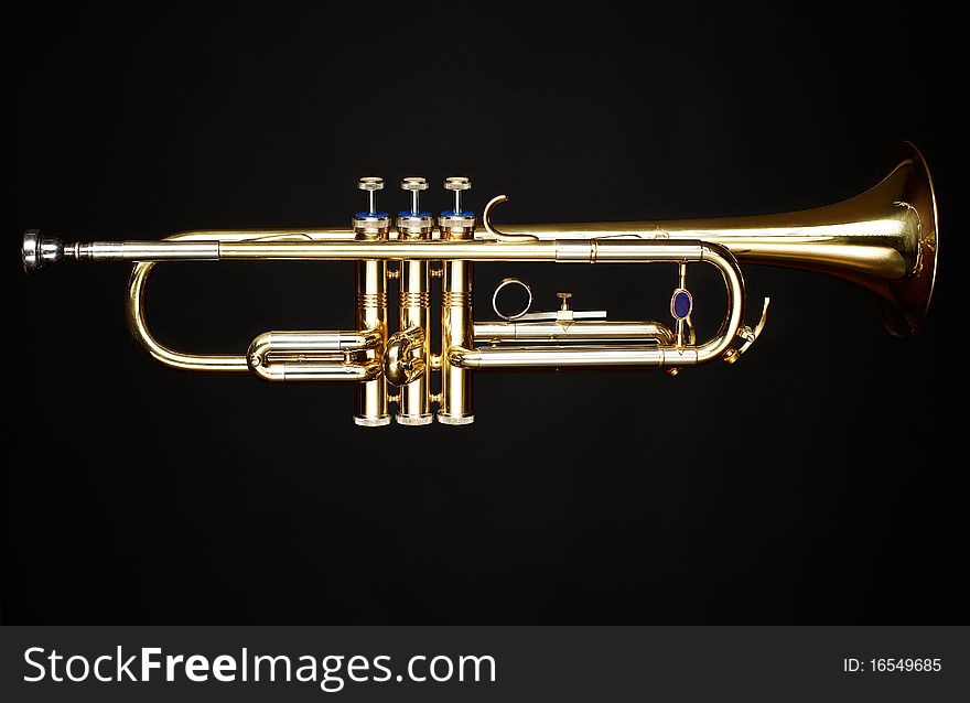 Brass trumpet over black background