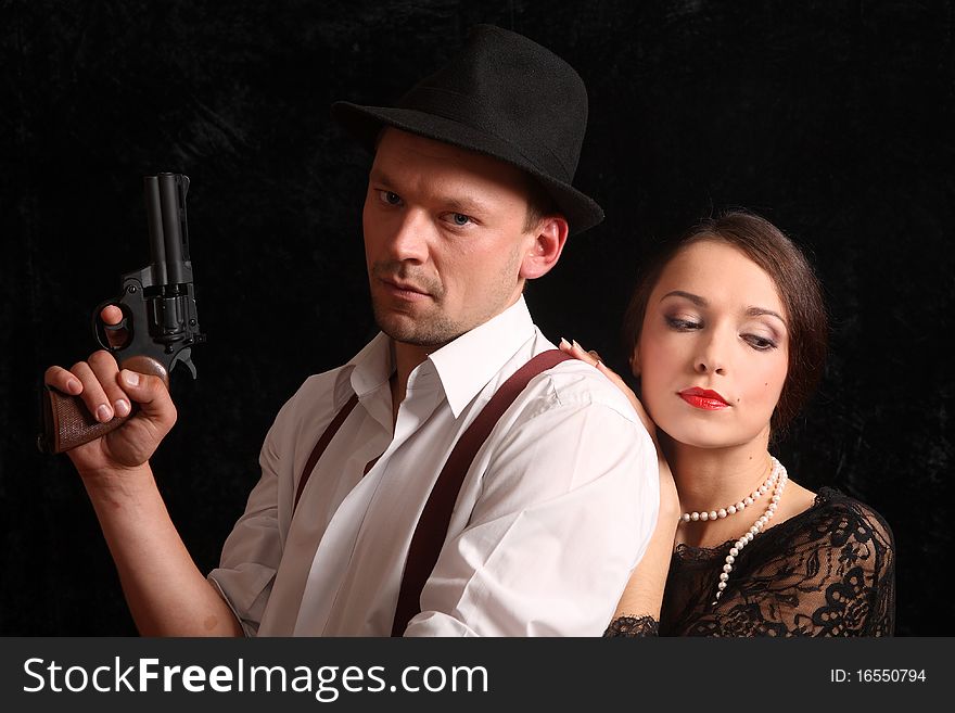 Portrait of the man in a hat with a pistol and the beautiful woman. In style of a retro.