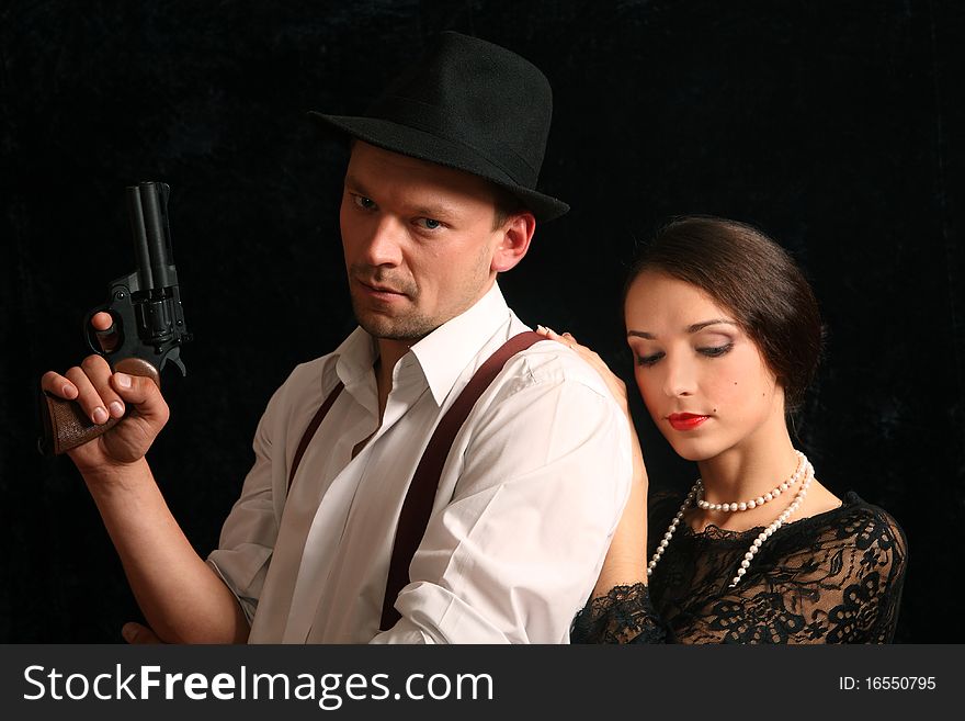 Portrait of the man in a hat with a pistol and the beautiful woman. In style of a retro.