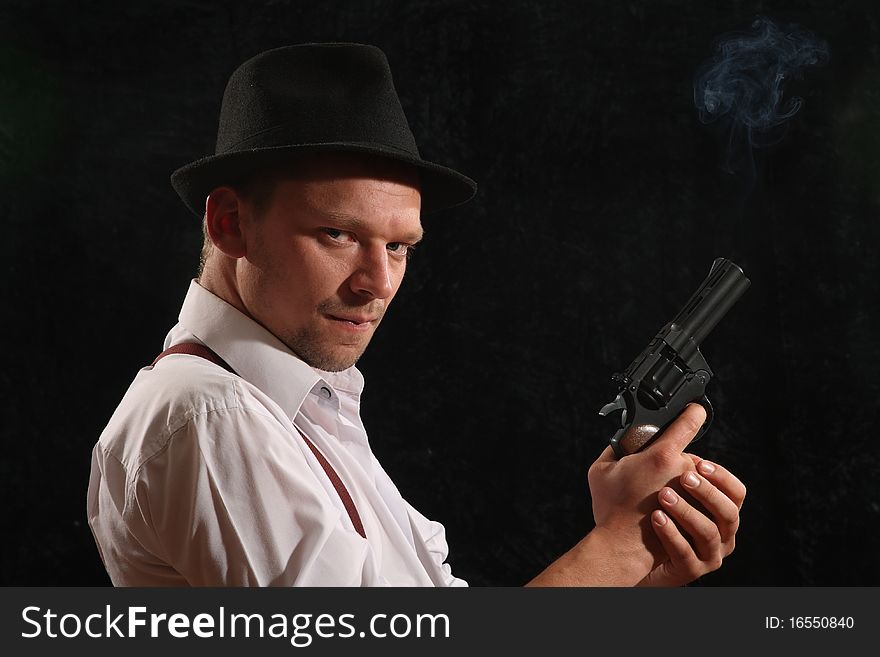The aggressive man-gangster with a pistol. A portrait on a black background.
