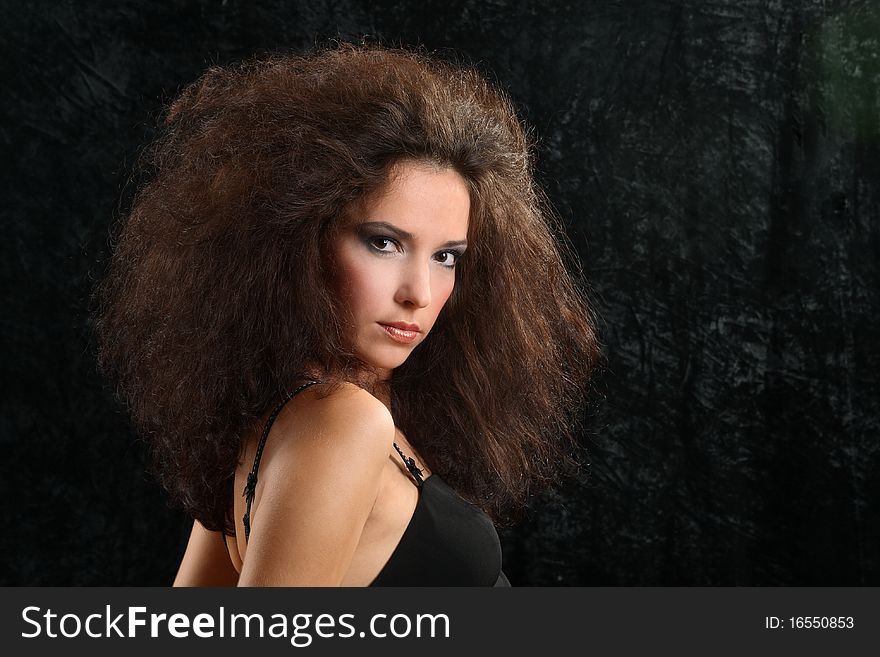 Portrait of the beautiful young woman with a magnificent hairdress on a black background.