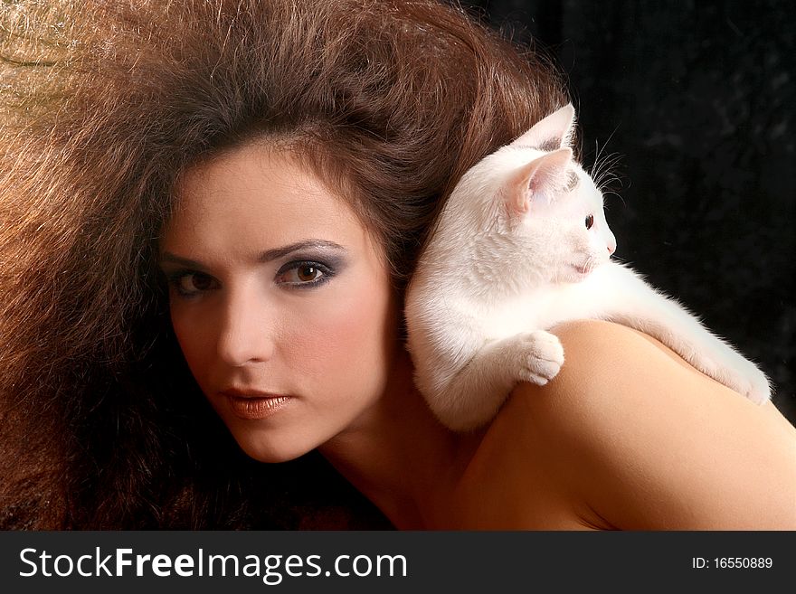 Portrait of the beautiful young woman with a magnificent hairdress And the WHITE CAT ON the SHOULDER on a black background.