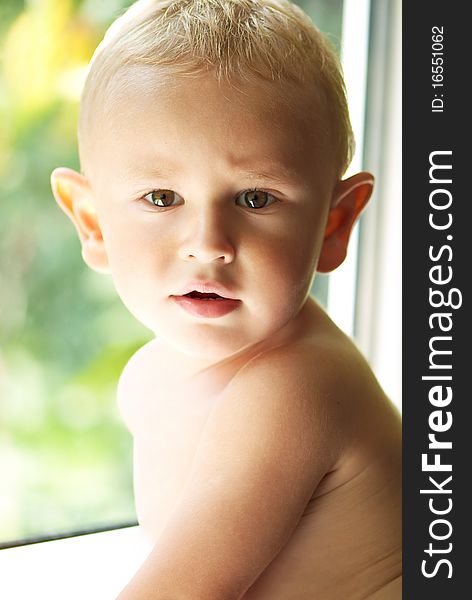 Amusing little boy near the sunny window