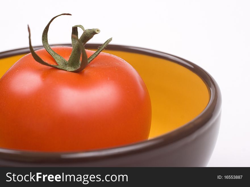 One tomato in a yellow with brown jar. One tomato in a yellow with brown jar