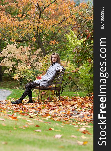 Girl on small bench in autumn park