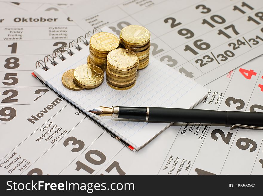 Sheets of a calendar with coins and a notebook