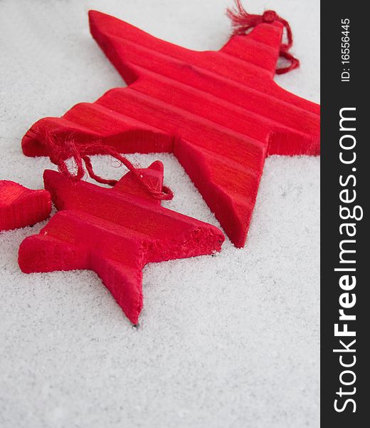 Christmas time concept: wooden red Christmas star decorations in different sizes, laying on the snowy background (isolated) *RAW format available at request. Christmas time concept: wooden red Christmas star decorations in different sizes, laying on the snowy background (isolated) *RAW format available at request