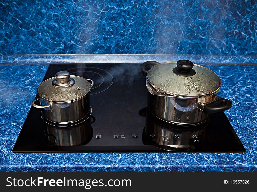 Two metal pans boil on a stove