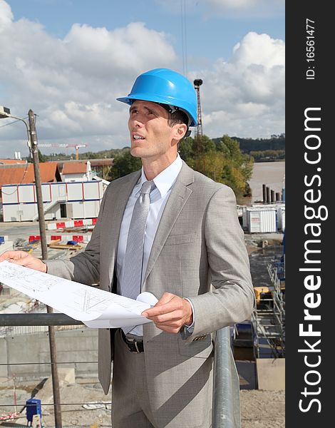 Architect with plan on building site