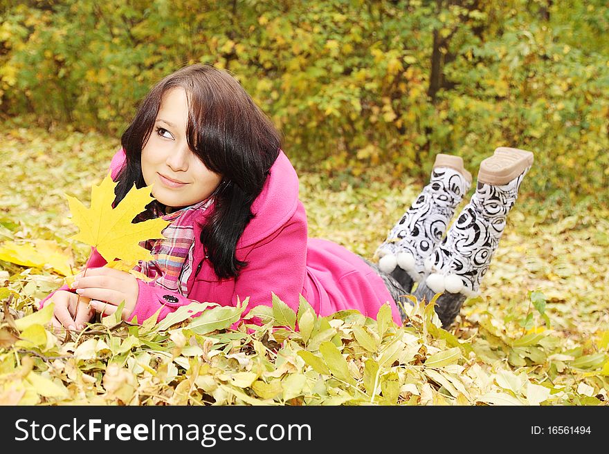 Smiling girl lies on the yellow the foliage