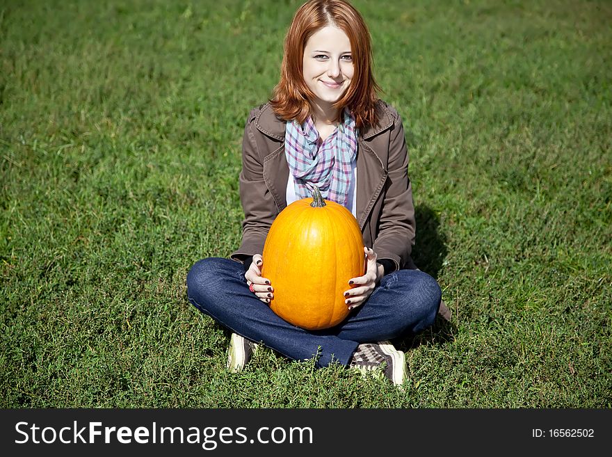 Woman Sitting At Green Grass And Keeping Pumpkin.