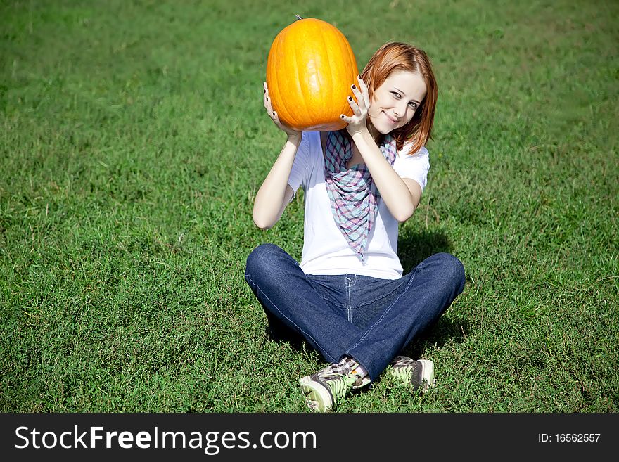 Women Sitting At Green Grass And Keeping Pumpkin.