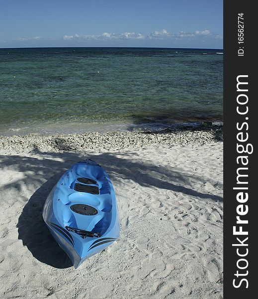 Blue kayak on sand of Mexican Caribbean beach with palm tree shadow. Blue kayak on sand of Mexican Caribbean beach with palm tree shadow