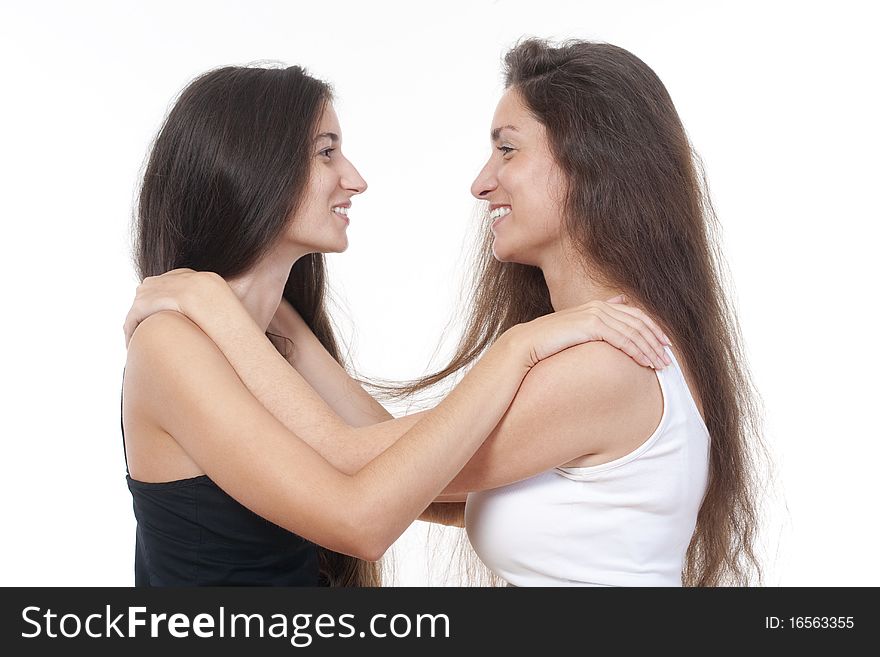 Two sisters with long brown hair embracing each other, smiling. Two sisters with long brown hair embracing each other, smiling