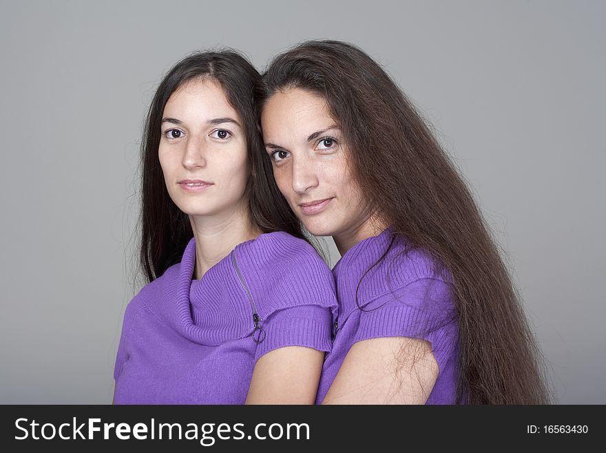 Portrait of two sisters with very long brown hair -isolated on gray