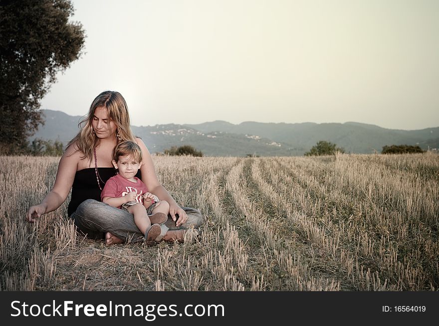 Mother and son at a crop field lightened up by the sunset.