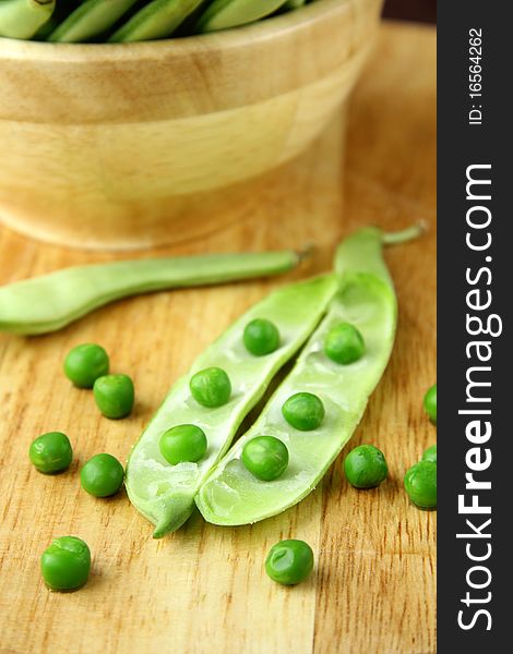 Green peas in a wooden bowl and on the board