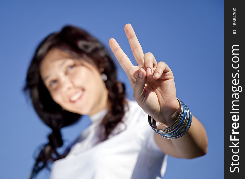 Portrait of beautiful brunette girl with blue eyes which show hand V symbol. Portrait of beautiful brunette girl with blue eyes which show hand V symbol.