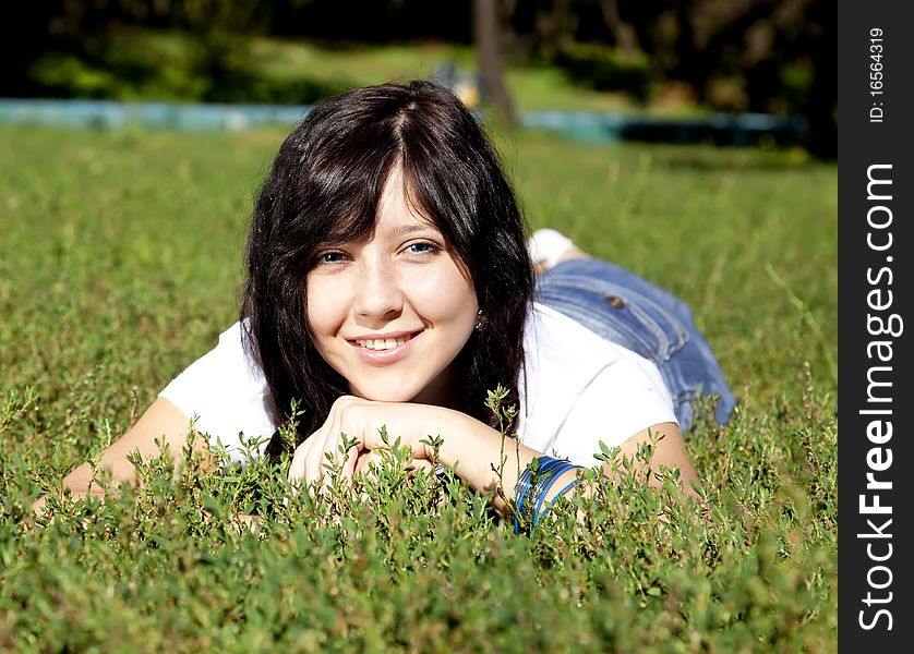 Girl with blue eyes on green grass in the park.