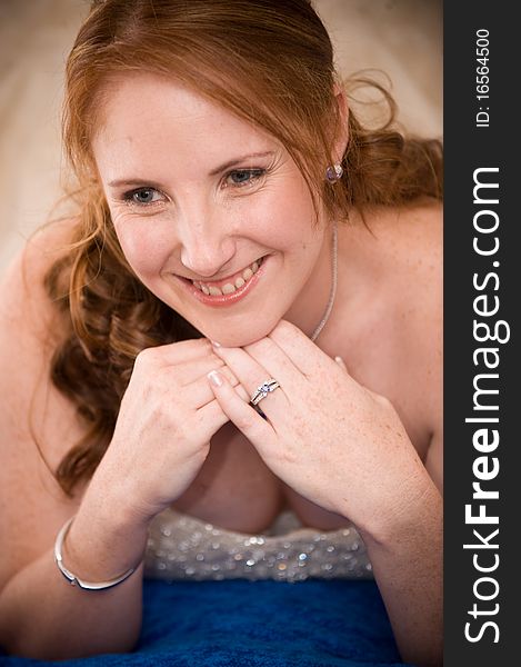 Red head beautiful bride laying down on her elbows with cleavage visible and leaning on her hands whilst smiling. Red head beautiful bride laying down on her elbows with cleavage visible and leaning on her hands whilst smiling