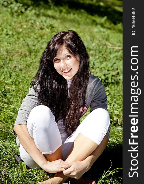 Portrait of beautiful brunette girl with blue eyes on green grass in the park. Portrait of beautiful brunette girl with blue eyes on green grass in the park.